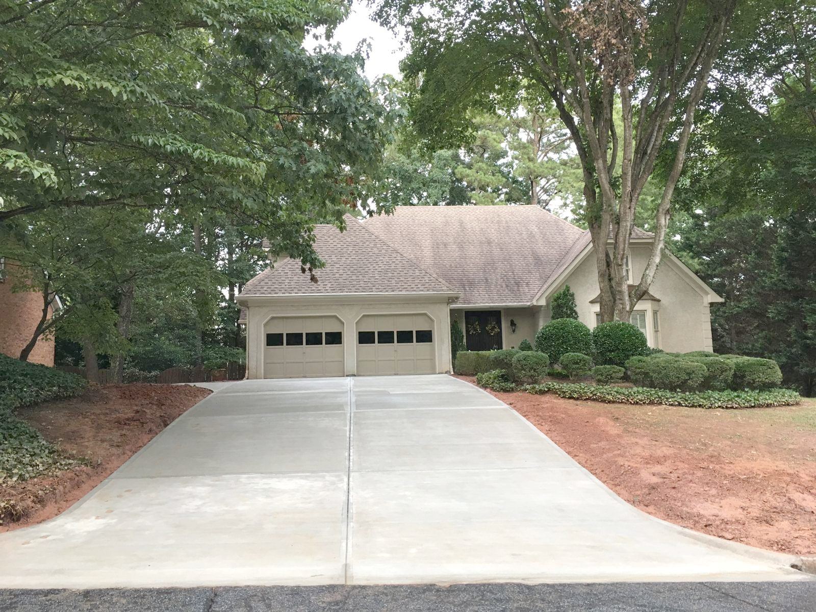 Freshly poured concrete driveway leading to a two-car garage