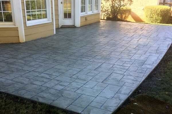 Gray stamped concrete patio with a stone pattern behind a home in Gwinnett County, GA
